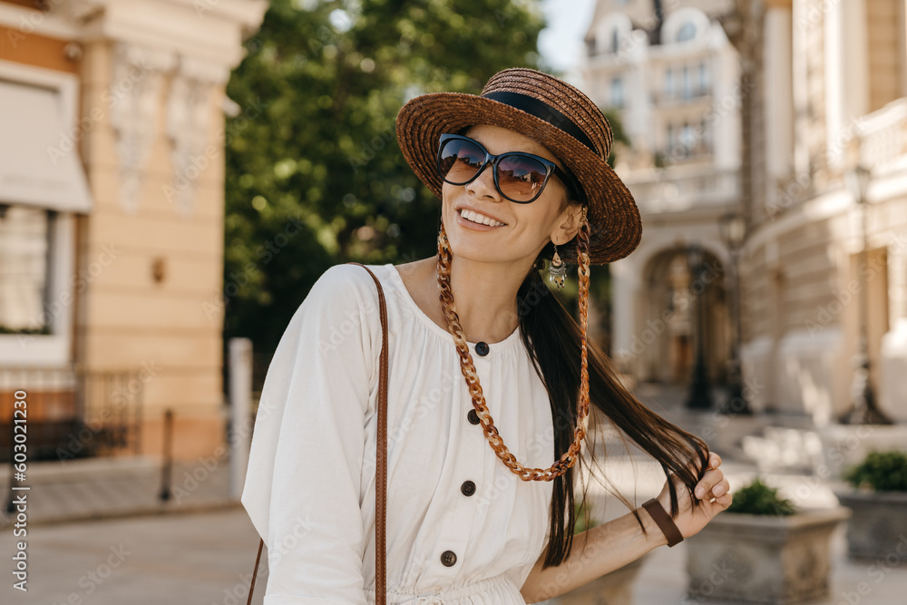 Fototapeta premium beautiful woman walking in street on vacation dressed in white summer fashion dress
