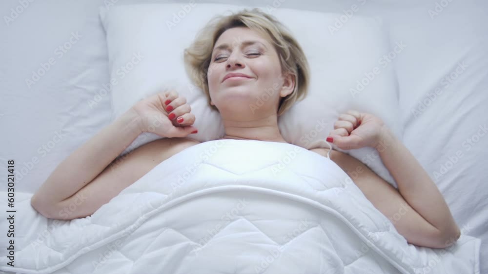 Pretty smiling woman had great night's sleep in her comfortable soft bed, stretching sweetly and enjoying slow awakening on the weekend, top-view Pretty smiling woman had great night's sleep in her comfortable soft bed, stretching sweetly and enjoying slow awakening on the weekend, top-view