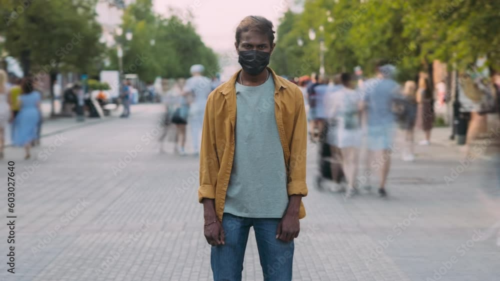 Zoom-in time lapse portrait of Indian person in medical mask standing in urban street during corona virus pandemic. People and healthcare concept. Zoom-in time lapse portrait of Indian person in medical mask standing in urban street during corona virus pandemic. People and healthcare concept.