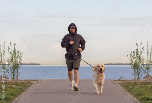 A man on a morning run with his golden retriever. Sports in the early morning. 