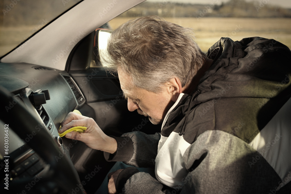 Older man take care annd cleaning car interior on nature parking Older man take care annd cleaning car interior on nature parking