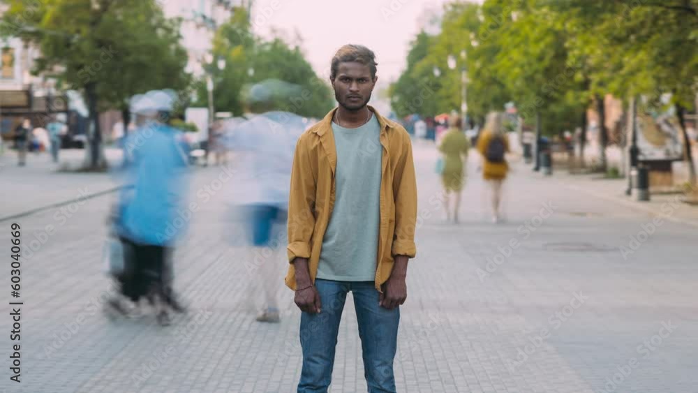 Zoom-out time lapse portrait of Indian person standing in pedestrian area while crowd of people walking around. Youth and urban life concept. Zoom-out time lapse portrait of Indian person standing in pedestrian area while crowd of people walking around. Youth and urban life concept.