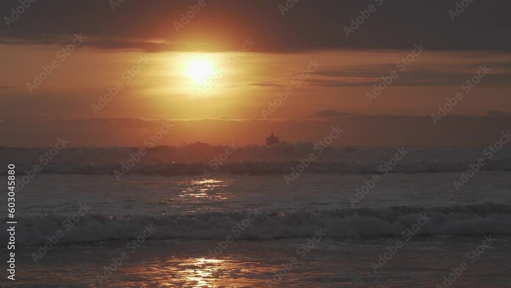 romantic sunset over a sandy beach at coastline of the pacific ocean in the Atacama desert of Chile near Arica with the silhouette of a ship at the horizon.