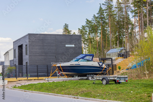 Beautiful view of modern European country villa in countryside with parked boat on house yard. Sweden.