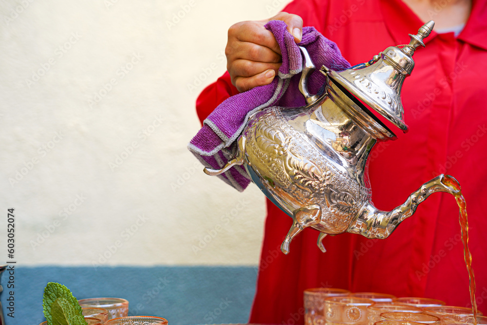 unrecognizable arabic woman holds a teapot with green tea. typical moroccan drink