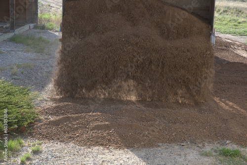 Front-end loader of large industrial excavator dumping road mix at a construction site.