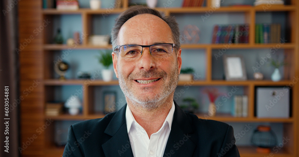 Smiling happy confident handsome smart middle aged entrepreneur, businessman posing in office. Close up face of bearded professional businessman in eyeglasses turning and looking at the camera Smiling happy confident handsome smart middle aged entrepreneur, businessman posing in office. Close up face of bearded professional businessman in eyeglasses turning and looking at the camera
