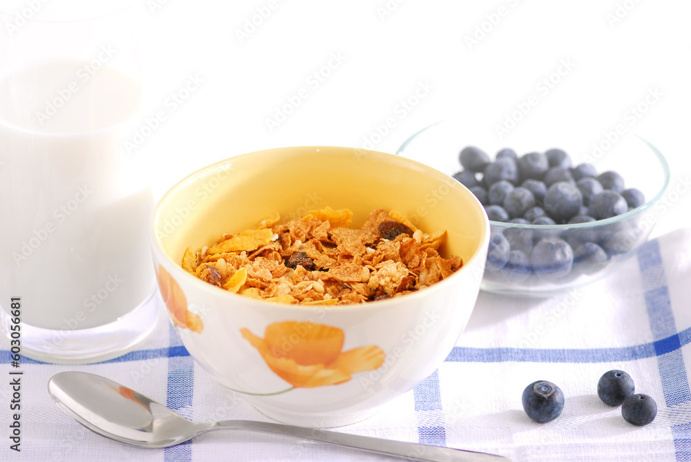 Healthy breakfast of cereal, milk and blueberries served on a table on sunny morning Healthy breakfast of cereal, milk and blueberries served on a table on sunny morning