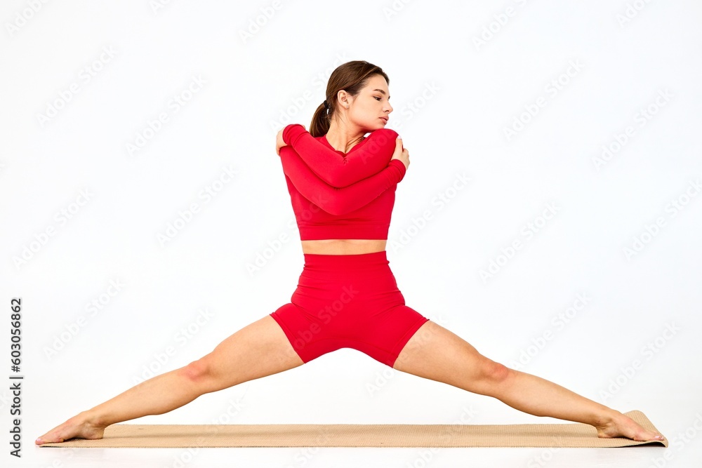 In a minimalist indoor space, a dedicated yoga coach dressed in a vibrant red tracksuit In a minimalist indoor space, a dedicated yoga coach dressed in a vibrant red tracksuit