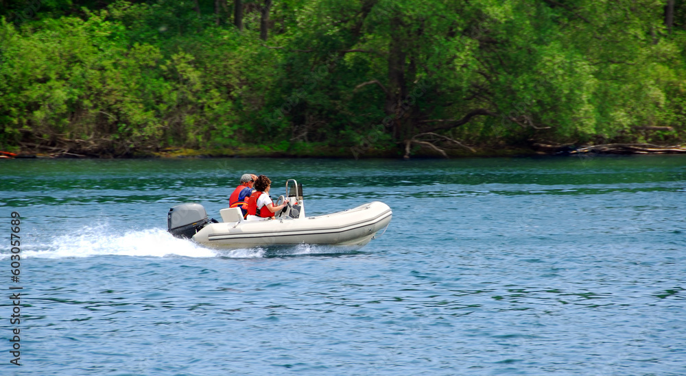 Fototapeta premium A couple driving an inflatable boat on a river