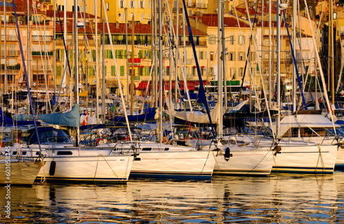 The Vieux Port (old port) in the city of Cannes in the French riviera, as the first rays of the morning sun illuminate the marina and the buildings behind the boats. photo