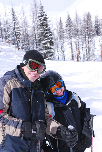 Father and daughter enjoying downhill skiing in winter mountains