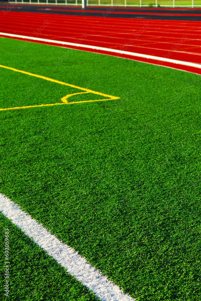 Obraz premium Red racetrack and green sports field with artificial grass