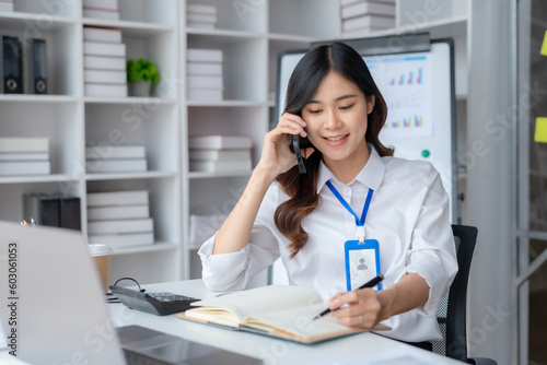 Happy beautiful smiling Asian businesswoman talking on mobile phone while working in office. Asian businesswoman making telephone call at office , enjoying talk, communication