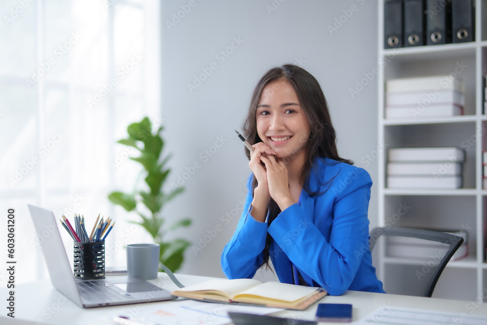 Successful Asian businesswoman smiling using laptop and computer at office. Confident Asia businesswoman sitting happily in the office. Successful Asian businesswoman smiling using laptop and computer at office. Confident Asia businesswoman sitting happily in the office.