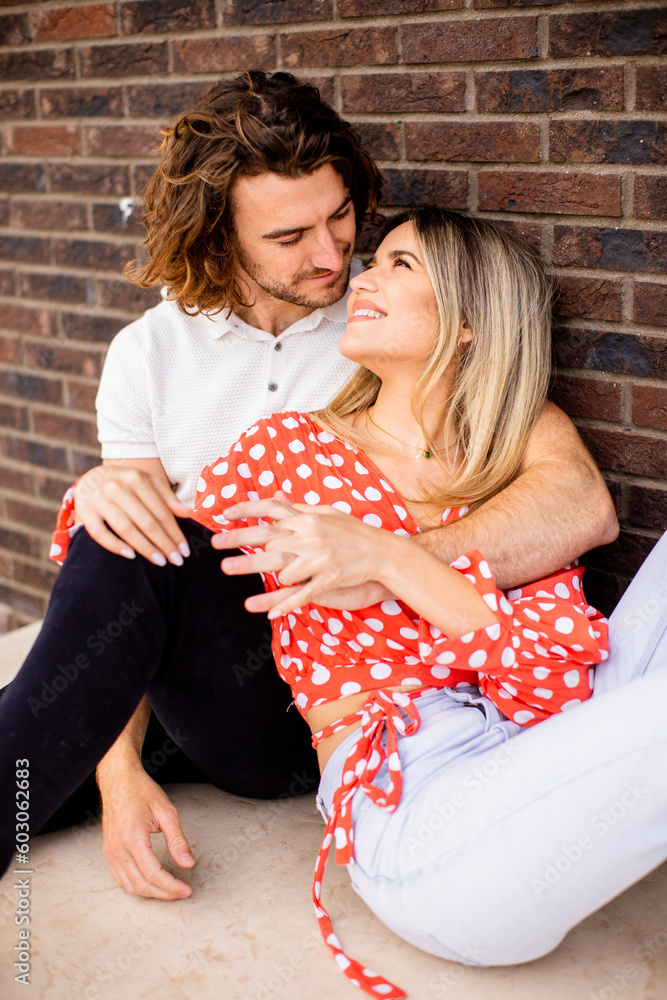 Smiling young couple in love in front of house brick wall Smiling young couple in love in front of house brick wall