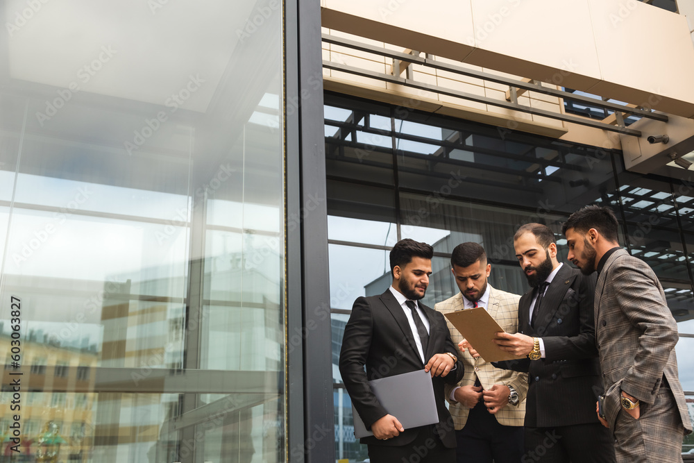 An international team of successful young business men in suits at a meeting are discussing the implementation of business plans together. Effective management and professional organization An international team of successful young business men in suits at a meeting are discussing the implementation of business plans together. Effective management and professional organization