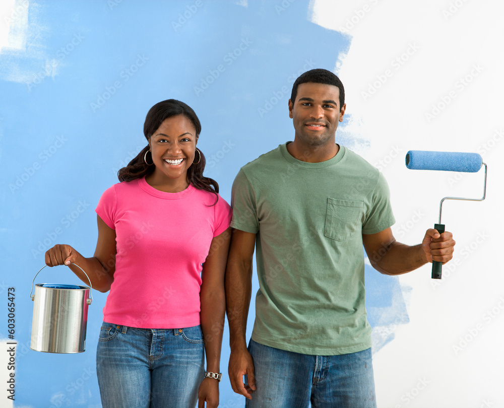 African American couple next to half-painted wall with paint supplies-American Gothic-style. African American couple next to half-painted wall with paint supplies-American Gothic-style.