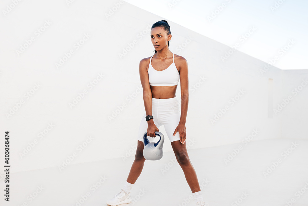 Slim woman practicing with a kettlebell in the white outdoor studio. Young female doing strength training outdoors. Slim woman practicing with a kettlebell in the white outdoor studio. Young female doing strength training outdoors.