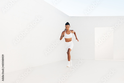 Woman runner in white fitness clothes. Full length on fitness influencer sprinting.