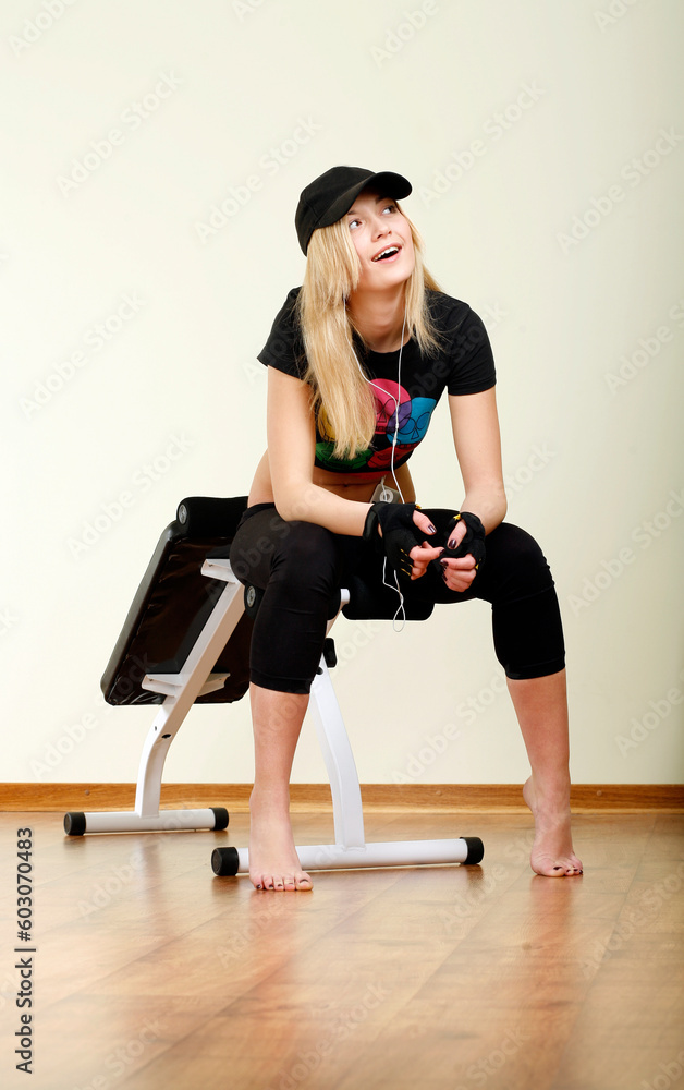 smiling girl in cap sitting on fitness machine