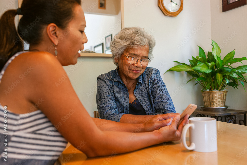 © ByLorena/Stocksy - Adult daughter helping her mother with cellphone