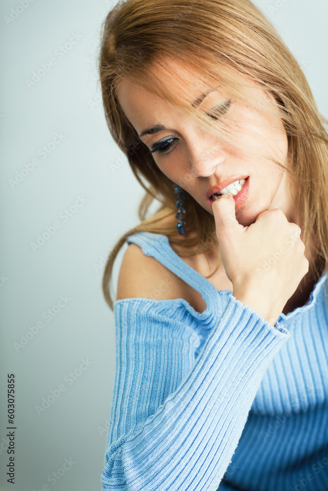 portrait of 30 years old woman biting her fingernails on cyan background. Vertical shape, Copy space portrait of 30 years old woman biting her fingernails on cyan background. Vertical shape, Copy space