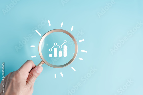 Hand holding magnifier to analysis portfolio management with lightbulb icon for planning development leadership and customer target and thinking idea creative concept.