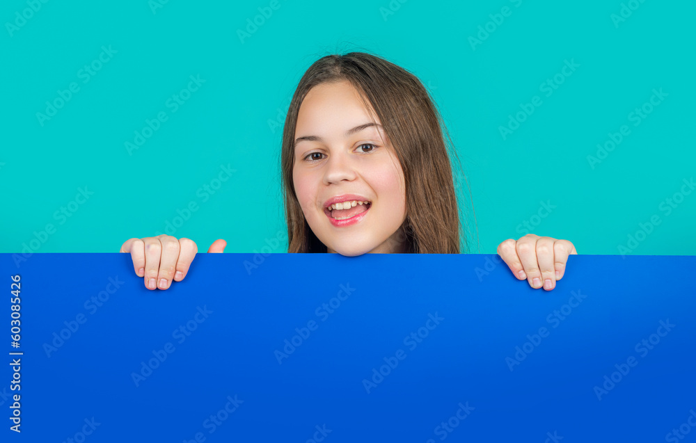 cheerful kid behind blank blue paper with copy space for advertisement cheerful kid behind blank blue paper with copy space for advertisement