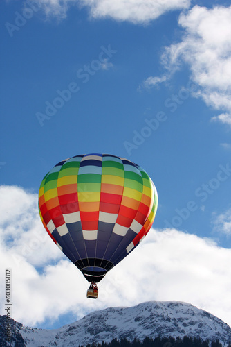 Colorful hot air balloon flying against a blue sky background © Designpics