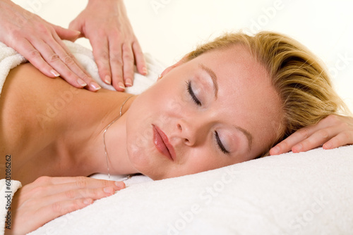 Attractive blond woman laying on stomach with a relaxed expression showing hands of another woman giving a massage