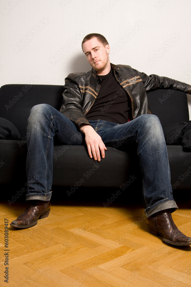 young man sitting on a black sofa young man sitting on a black sofa