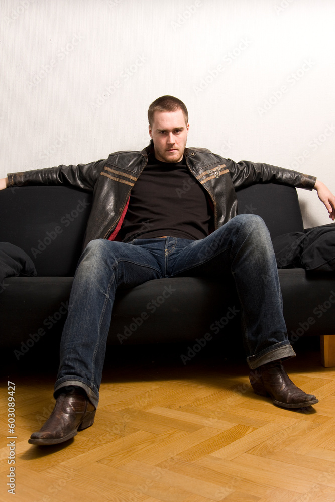 young man sitting on a black sofa young man sitting on a black sofa