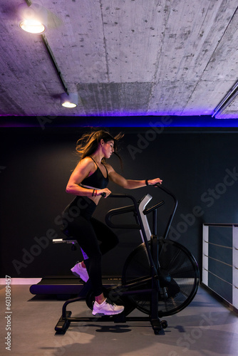 fit woman riding on air bicycle during cardio training in gym photo