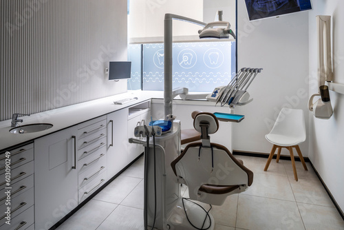 Modern dental practice room with chair, lamp and more equipment photo