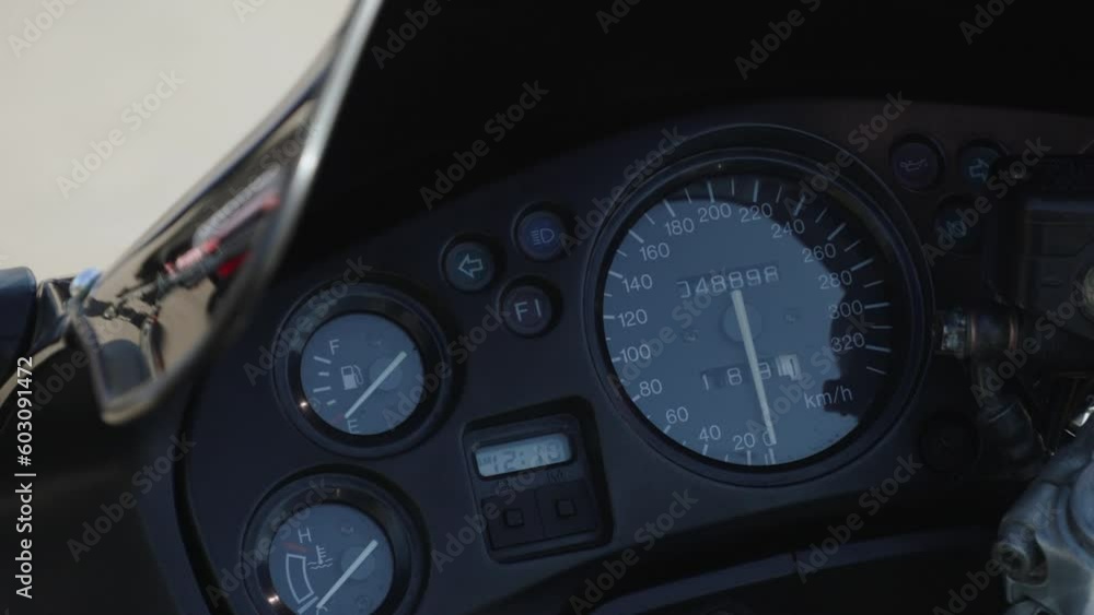Dashboard of powerful sports motorcycle with beautiful figure on odometer and speedometer. Aerodynamic protection of parked motorcycle reflects family with pram strolling on sunny day. Dashboard of powerful sports motorcycle with beautiful figure on odometer and speedometer. Aerodynamic protection of parked motorcycle reflects family with pram strolling on sunny day.
