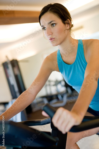A young woman using a cycling machine in the gym