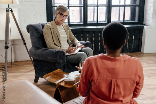 Psychotherapist listening about problems of patient during session  photo