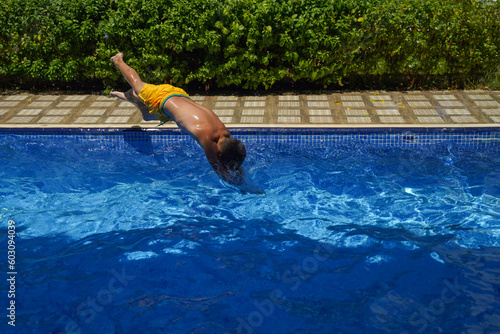 A child in flight over the pool. Jumping and flying freely. Tropical fun vacation.