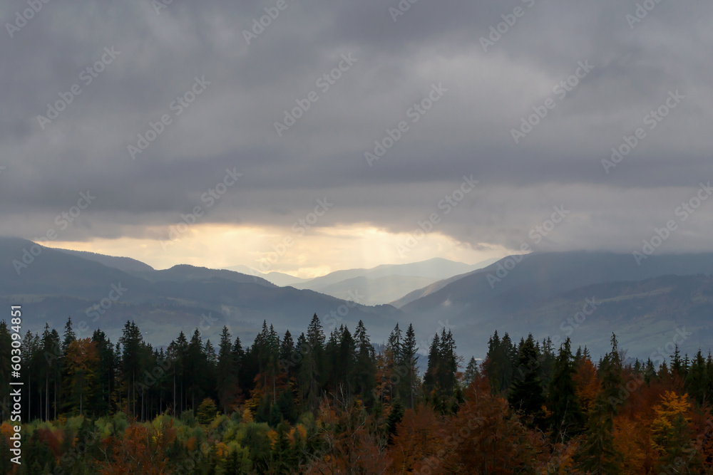 Autumn mountains under clouds, through which sun's rays break through. The beauty of the Carpathians. Tourism and travel