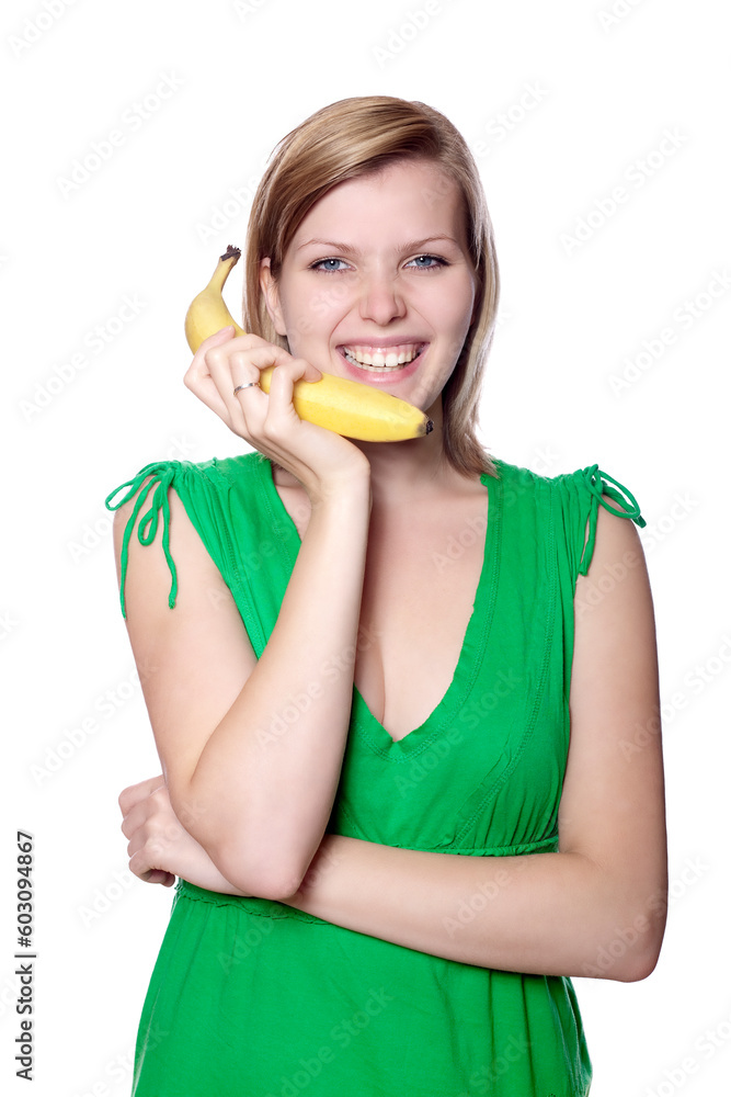Pretty girl in a green dress is holding a banana as a phone, isolated on white Pretty girl in a green dress is holding a banana as a phone, isolated on white