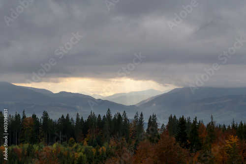 Autumn mountains under clouds, through which sun's rays break through. The beauty of the Carpathians. Tourism and travel
