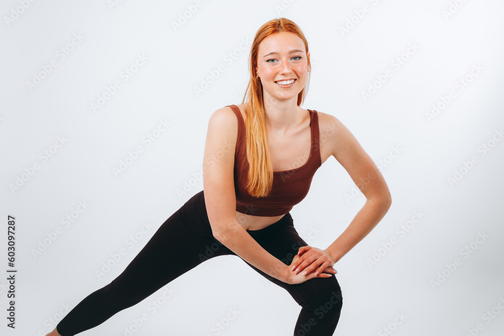 Full-length portrait of girl exercising by holding two hands on knee, stretching legs in squat, white background. Full-length portrait of girl exercising by holding two hands on knee, stretching legs in squat, white background.