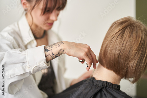 Crop hairstylist cutting hair of client in studio photo
