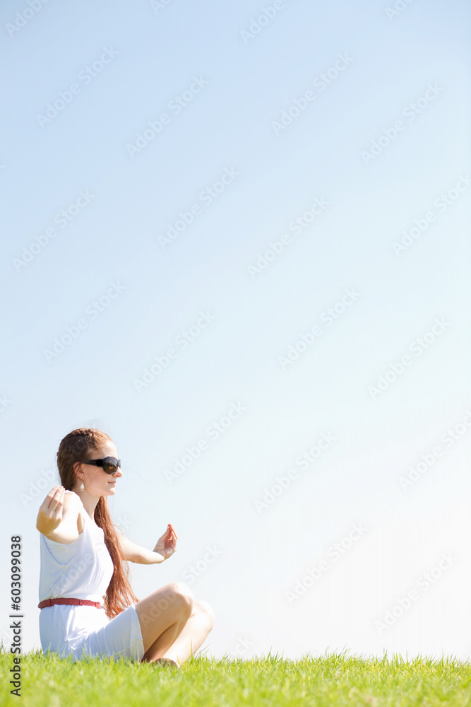 young women sitting on grass and doing meditating young women sitting on grass and doing meditating