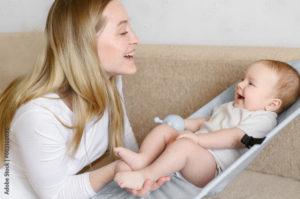 A happy baby lies in a children's deck chair, smiles and is happy to see mom,mom talks to the baby.Childhood,motherhoodd A happy baby lies in a children's deck chair, smiles and is happy to see mom,mom talks to the baby.Childhood,motherhoodd