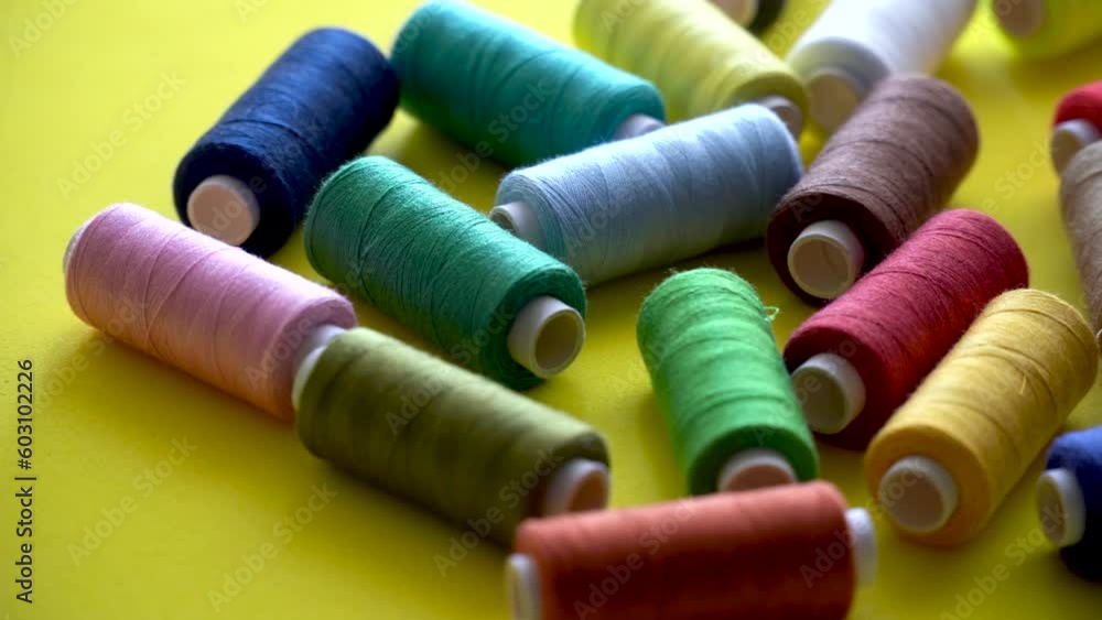: Close up of some thread spools in different colors, on a yellow background. : Close up of some thread spools in different colors, on a yellow background.