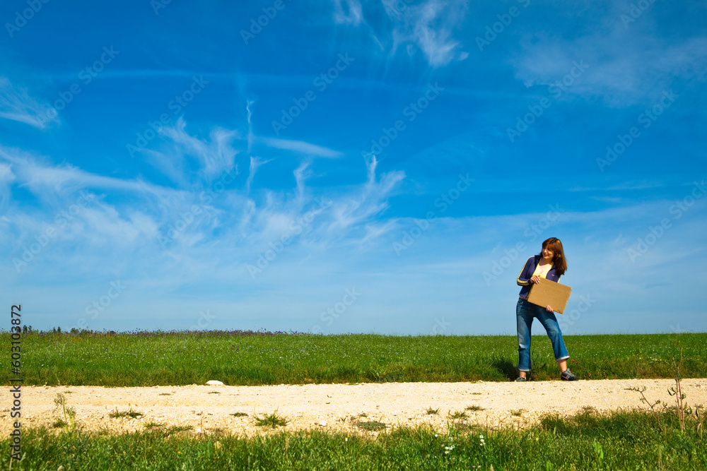 Young woman hitch hiking on a beautiful green meadow Young woman hitch hiking on a beautiful green meadow