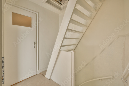 an empty room with white walls and stairs leading up to the second floor, which is in need of repair