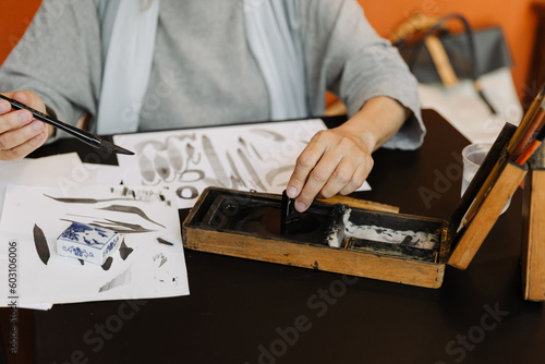 Senior woman using ink stick during calligraphy lesson photo